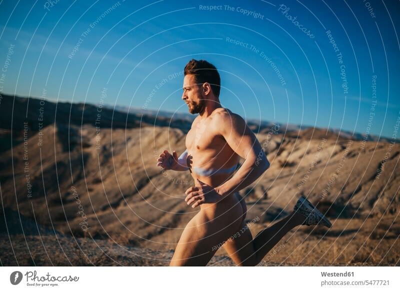 Naked handsome man running at desert against blue sky color image colour image Spain leisure activity leisure activities free time leisure time outdoors