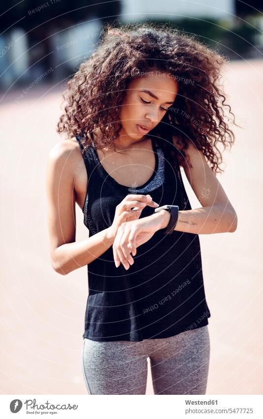 Sporty young woman looking at her smartwatch outdoors eyeing sportive sporting sporty athletic smart watch females women view seeing viewing sports Adults