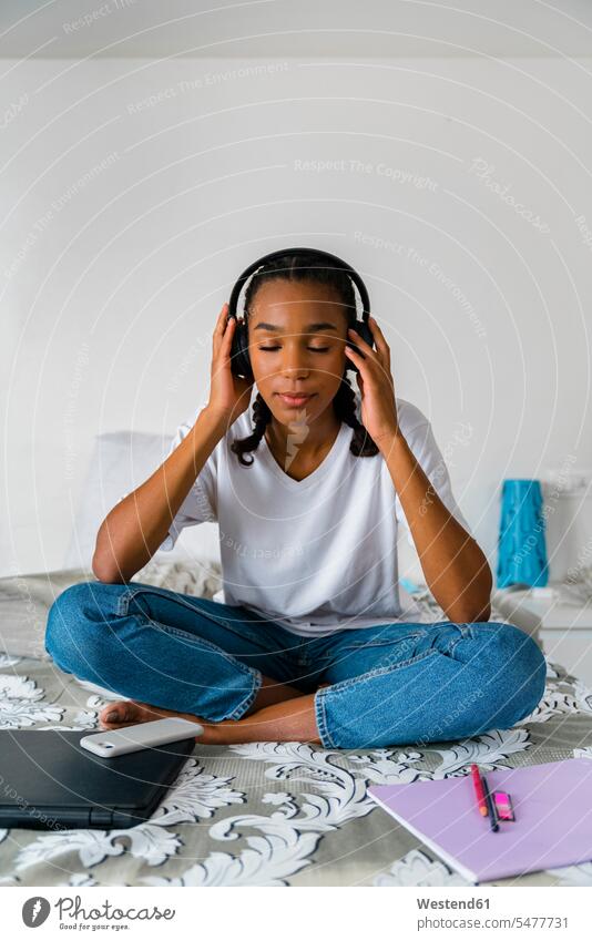 Teenage girl with cross legged listening to music while sitting at home color image colour image indoors indoor shot indoor shots interior interior view