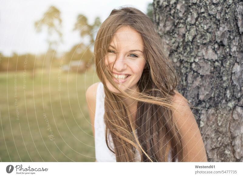 Portrait of laughing young woman leaning against tree trunk portrait portraits Laughter females women Tree Trunk Tree Trunks positive Emotion Feeling Feelings