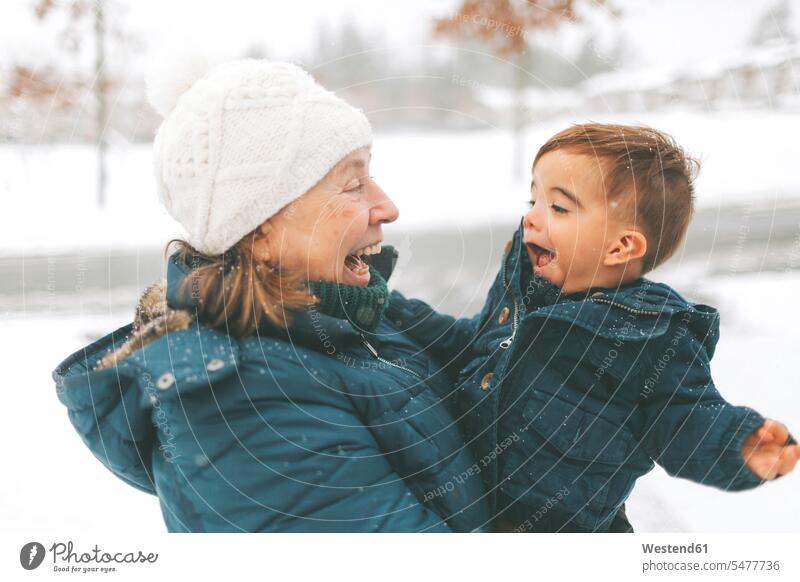 Grandmother and grandson hugging each other coat coats jackets hold smile play embrace Embracement seasons hibernal Ardor Ardour enthusiasm enthusiastic excited