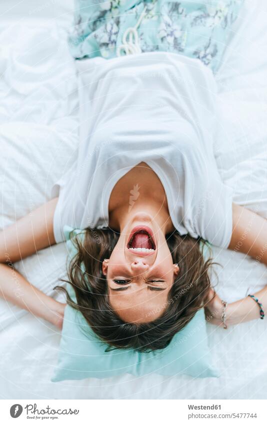 Top view of happy young woman lying in bed winking human human being human beings humans person persons celibate celibates singles solitary people