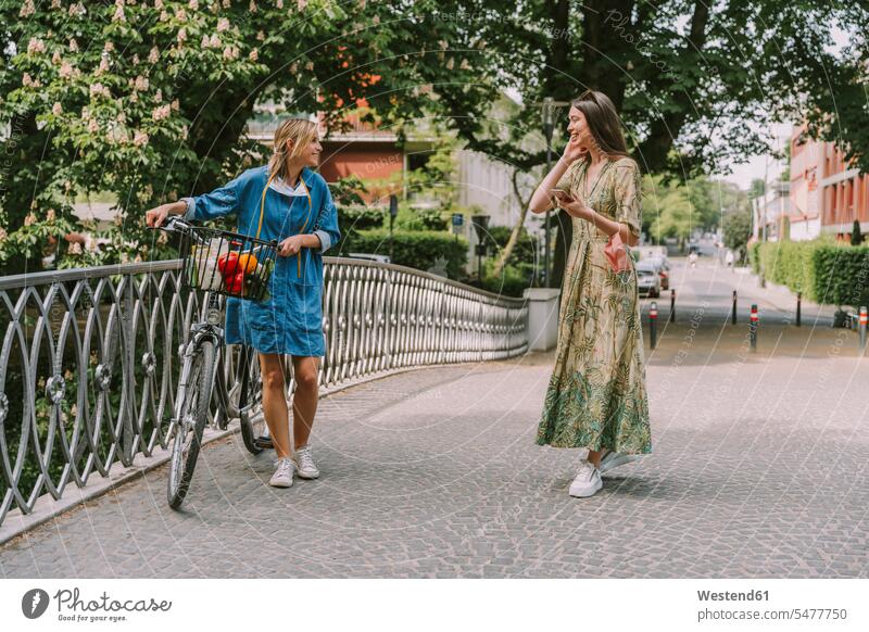 Two women with bicycle and face mask walking on a bridge friends mate female friend bikes bicycles bike - bicycle Cycle Cycle - Vehicle go going smile speak