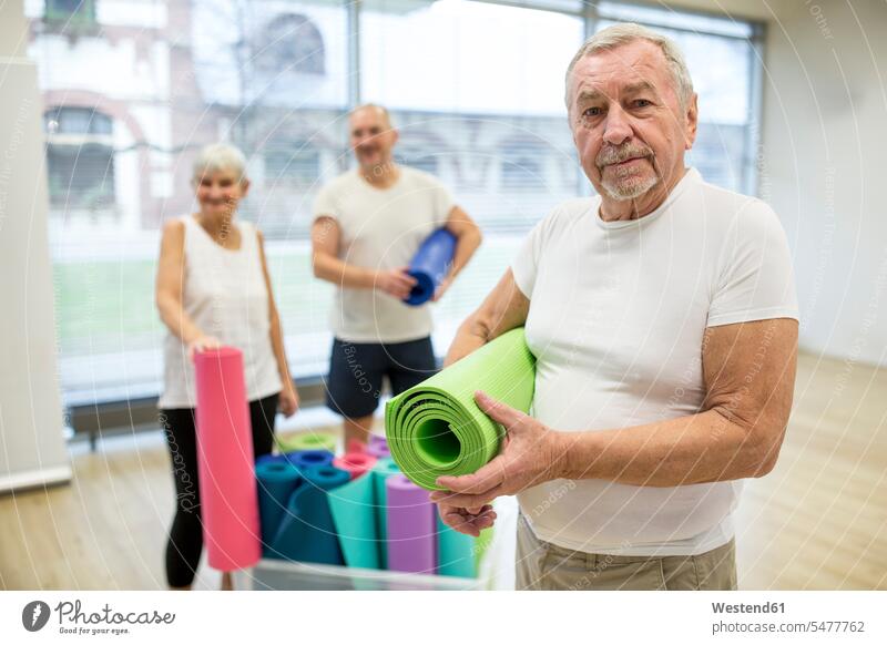 Happy senior man holding yoga mat after class smile happy stand Gymnastic Retired fit indoor indoor shot indoor shots interior interior view Interiors
