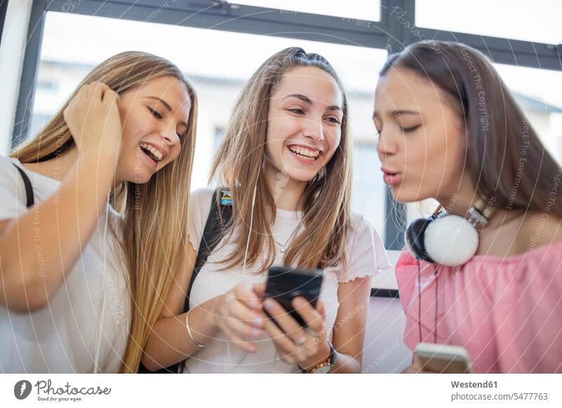 Happy teenage girls using cell phones in school happiness happy mobile phone mobiles mobile phones Cellphone student pupils schools Teenager Teens teenagers