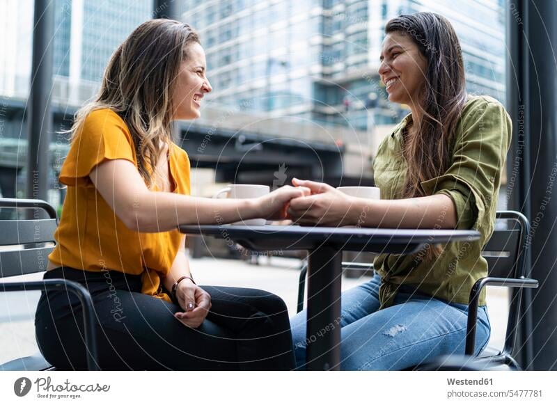 Happy lesbian couple at a sidewalk cafe in the city, London, UK smile Seated sit speak speaking talk relax relaxing relaxation delight enjoyment Pleasant