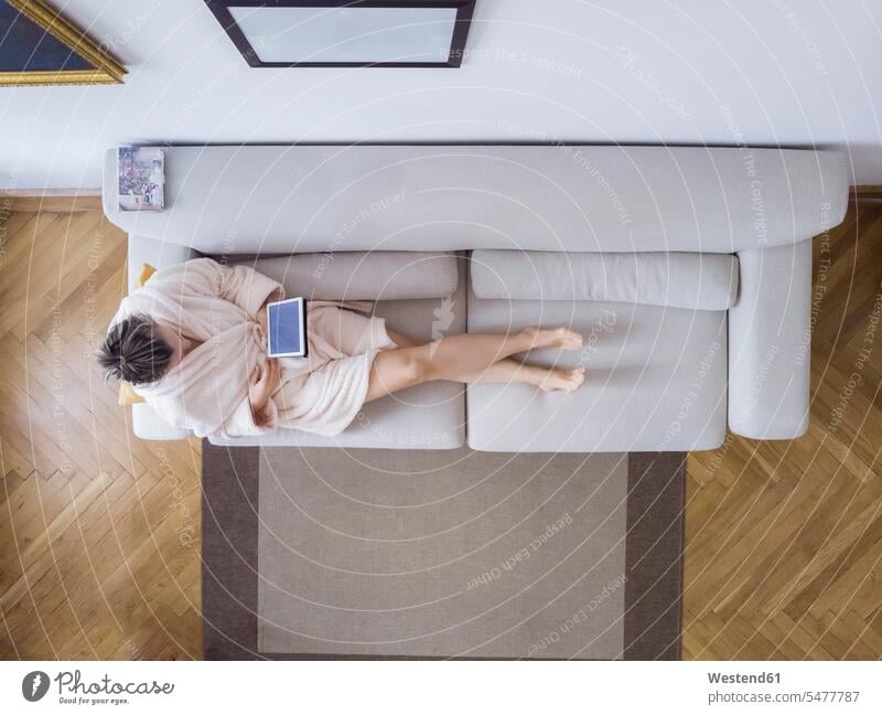 Mature woman in bathrobe sitting on the couch at home using digital tablet digitizer Tablet Computer Tablet PC Tablet Computers iPad Digital Tablet