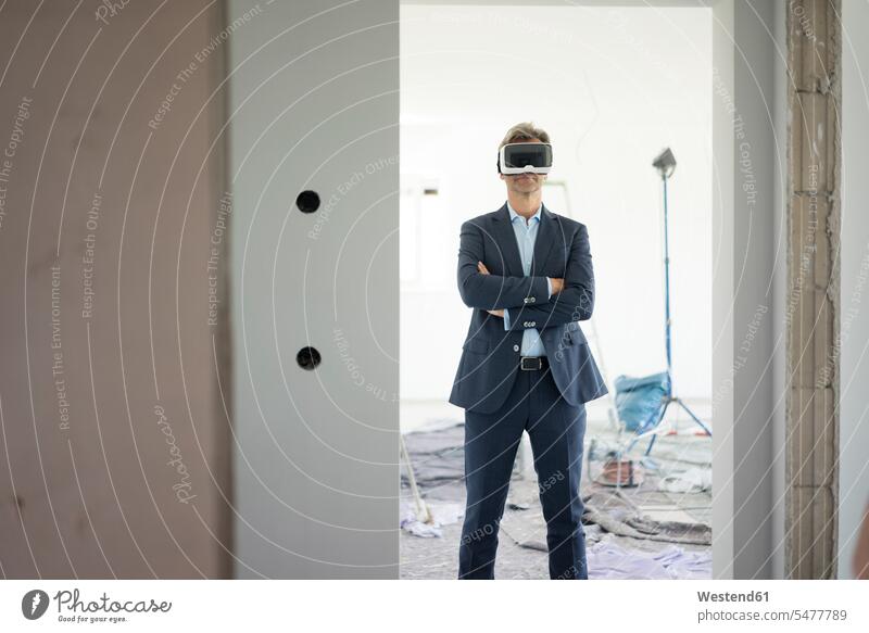 Man in suit wearing VR glasses in building under construction buildings man men males specs Eye Glasses spectacles Eyeglasses Fullsuit suits full suit virtual