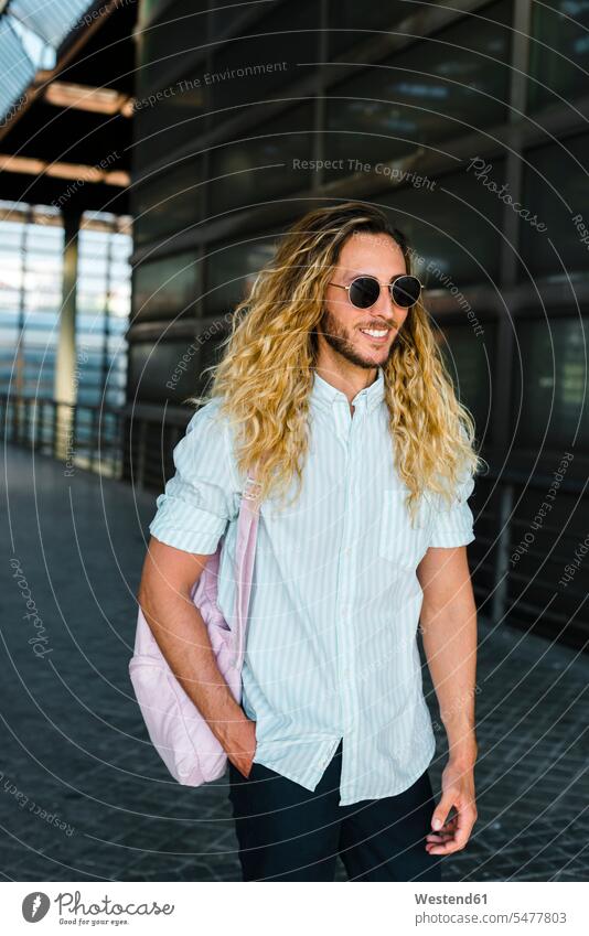 Smiling male hipster walking at railroad station color image colour image outdoors location shots outdoor shot outdoor shots day daylight shot daylight shots
