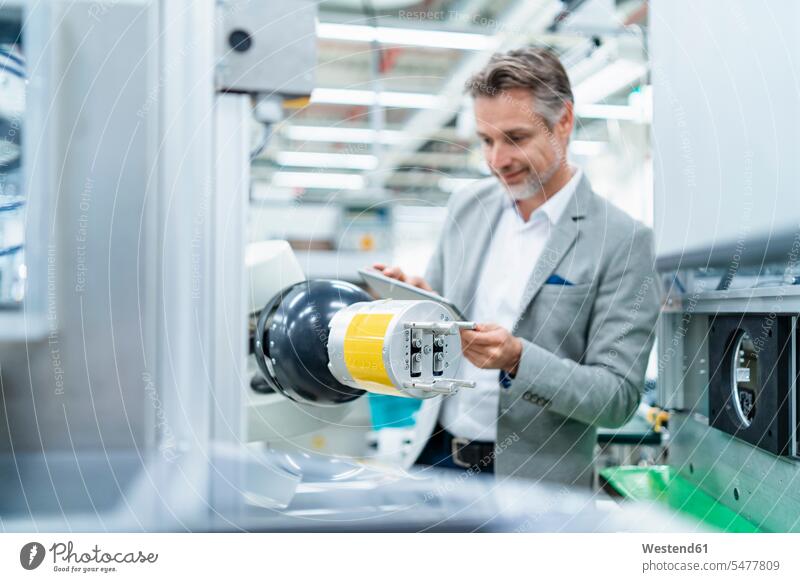 Businessman with tablet at assembly robot in a factory human human being human beings humans person persons caucasian appearance caucasian ethnicity european 1