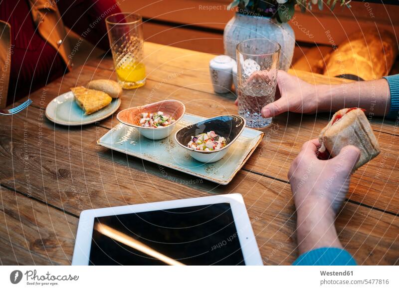 Two people sitting in restaurant, eating and drinling, with digital tablet on table Crockery Tableware Drinking Glass Drinking Glasses Bowls dish dishes Plates