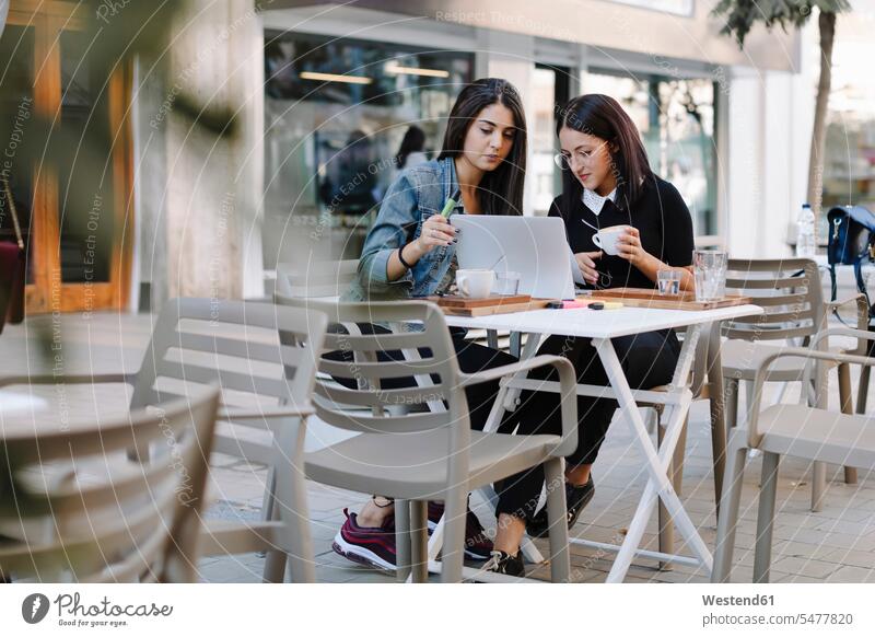Two friends sitting together at a pavement cafe using laptop business business world business life Wifi Wi-Fi wireless internet WLan wireless lan W-Lan