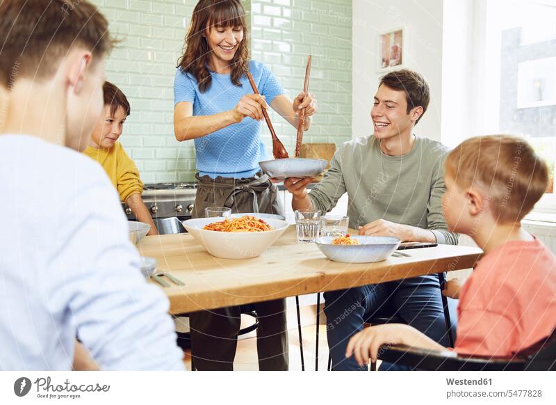 Mother eating spaghetti with her sons in the kitchen Bowls smile delight enjoyment Pleasant pleasure Cheerfulness exhilaration gaiety gay glad Joyous merry