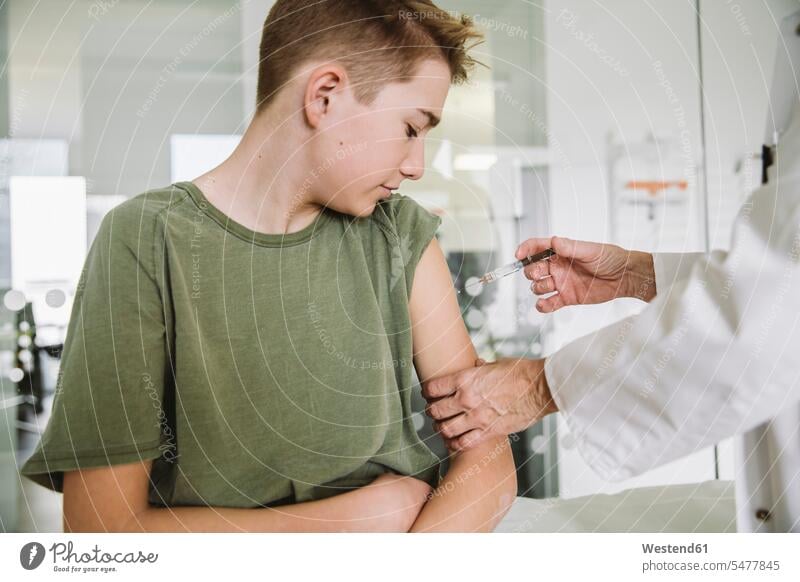 Doctor injecting vaccine into arm of teenager health healthcare Healthcare And Medicines medical medicine disease diseases ill illnesses sick Sickness patients