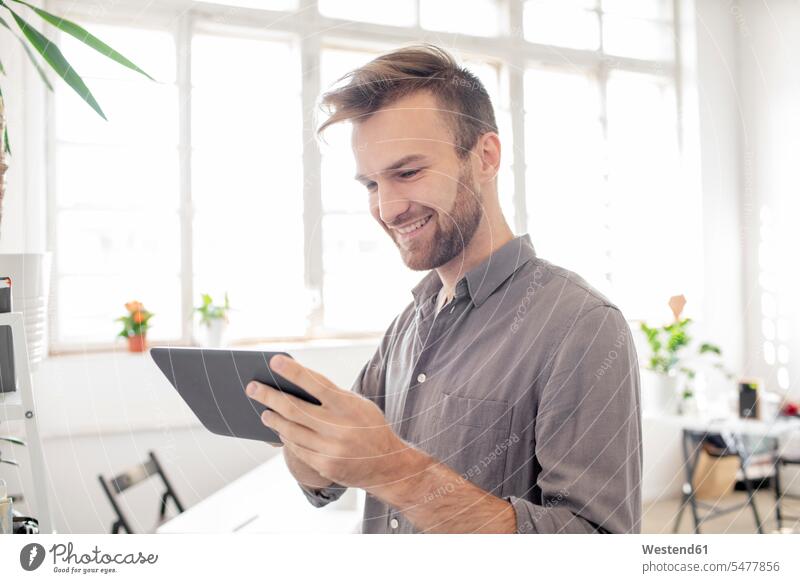 Smiling man using tablet in office Occupation Work job jobs profession professional occupation business life business world business person businesspeople