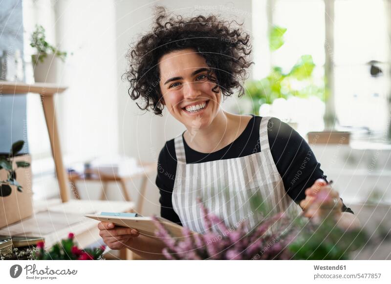 Portrait of happy young woman with clipboard in a small shop with plants human human being human beings humans person persons caucasian appearance