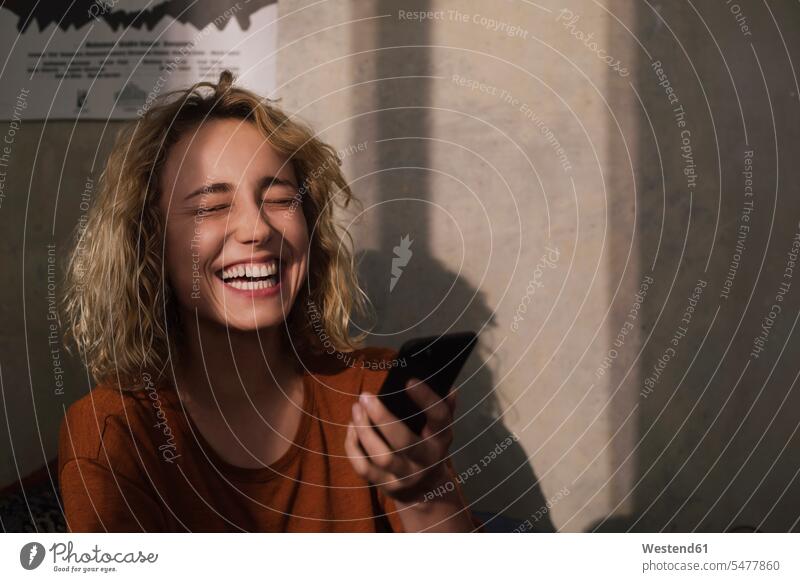 Portrait of laughing young woman with cell phone telecommunication phones telephone telephones cell phones Cellphone mobile mobile phones mobiles habitation