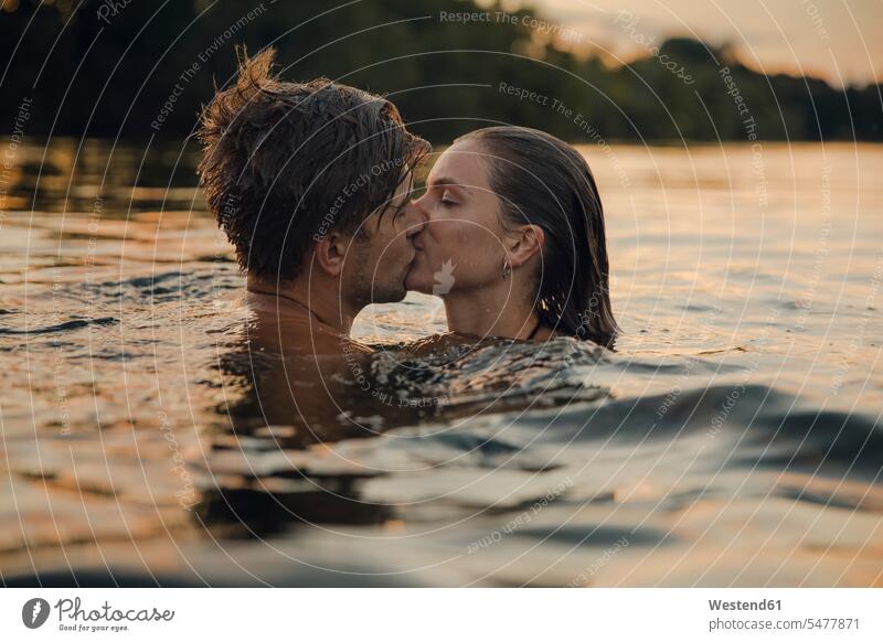 Young couple swimming in lake, kissing at sunset relax relaxing in the evening summer time summertime summery happy Emotions Feeling Feelings Sentiment
