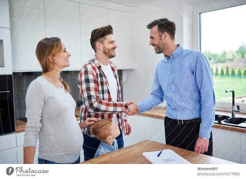 Family and real estate agent shaking hands in kitchen of new apartment flat flats apartments Handclasp Handclap family families realtor handshake people persons