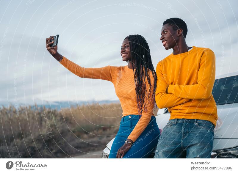 Smiling couple talking selfie while leaning on wall color image colour image outdoors location shots outdoor shot outdoor shots day daylight shot daylight shots