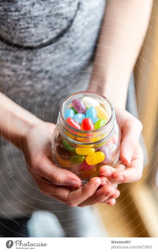 Glass of colourful sweet jellybeans on white wood, hands holding glass Sweets Candies Sweet Food abundance Abundant human hand human hands Sugary sweets
