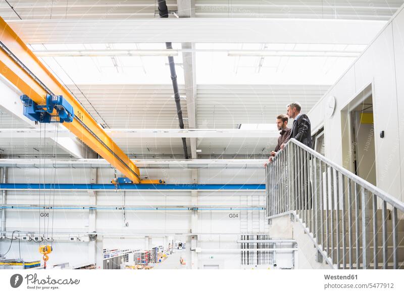 Two businessmen standing upstairs in a factory human human being human beings humans person persons caucasian appearance caucasian ethnicity european 2 2 people