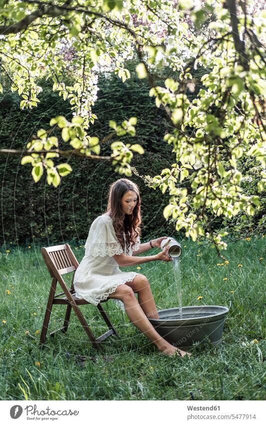 Young woman wearing white dress preparing footbath in garden females women Foot Bath footbaths colour colours Adults grown-ups grownups adult people persons