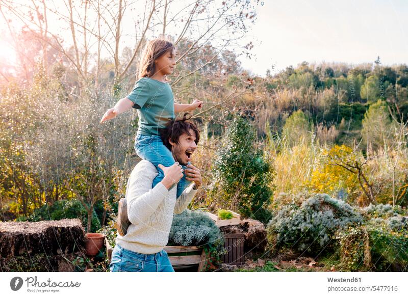 Father carrying son piggyback in a garden in the countryside playing gardens domestic garden messing about silly silliness piggy-back pickaback Piggybacking