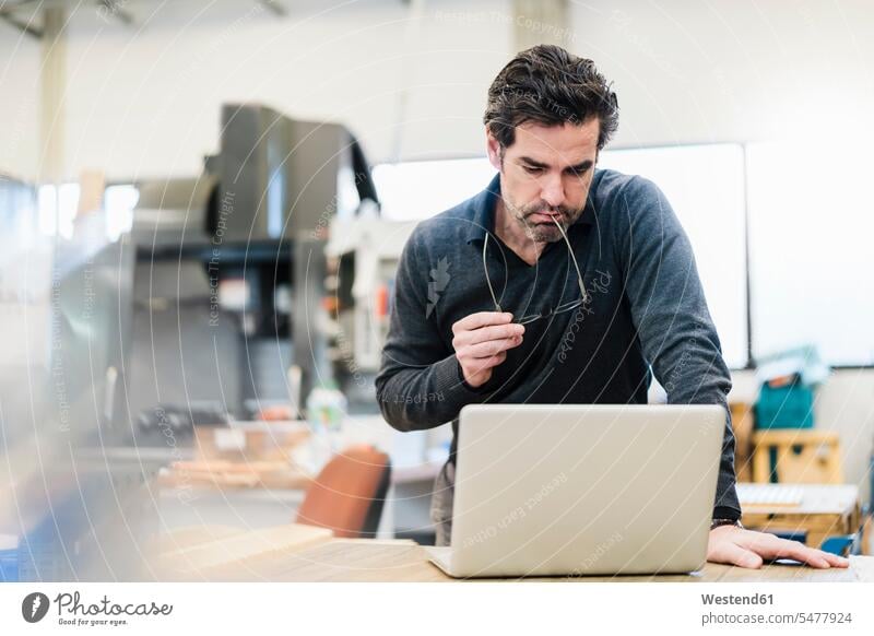 Businessman using laptop in a factory human human being human beings humans person persons caucasian appearance caucasian ethnicity european 1 one person only