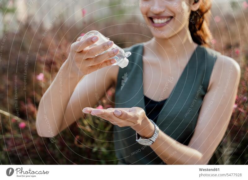 Close-up of smiling businesswoman washing hands with sanitizer while standing outdoors color image colour image Spain location shots outdoor shot outdoor shots