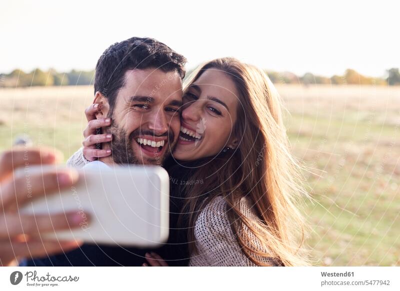 Happy couple taking a selfie in a park happiness happy parks Selfie Selfies twosomes partnership couples people persons human being humans human beings
