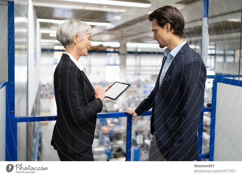 Businessman and senior businesswoman with tablet talking in a factory speaking digitizer Tablet Computer Tablet PC Tablet Computers iPad Digital Tablet