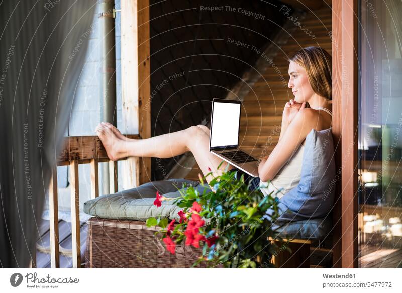 Woman relaxing on balcony using laptop woman females women balconies relaxed relaxation Laptop Computers laptops notebook Adults grown-ups grownups adult people