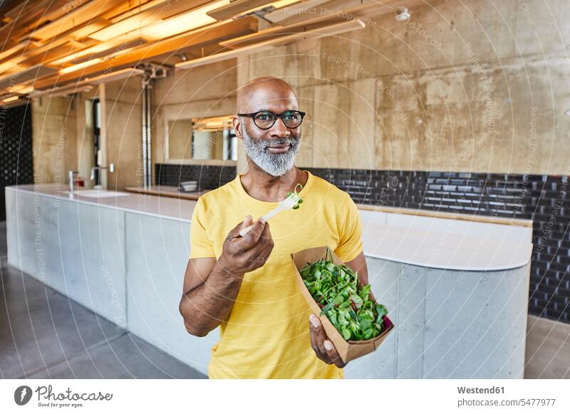 Mature businessman having a salad in modern office lettuce Salad eating contemporary offices office room office rooms Businessman Business man Businessmen