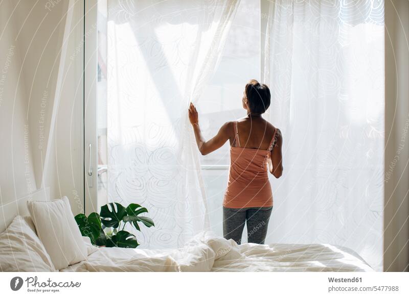 Woman standing at the window in bedroom at home human human being human beings humans person persons celibate celibates singles solitary people solitary person