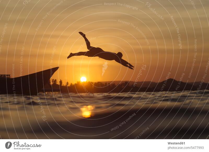 Indonesia, Lombok, man jumping into water sunset sunsets sundown men males Sea ocean vacation Holidays Leaping atmosphere atmospheric mood moody