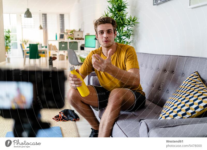 Fitness trainer live streaming fitness session while sitting on sofa at home color image colour image indoors indoor shot indoor shots interior interior view