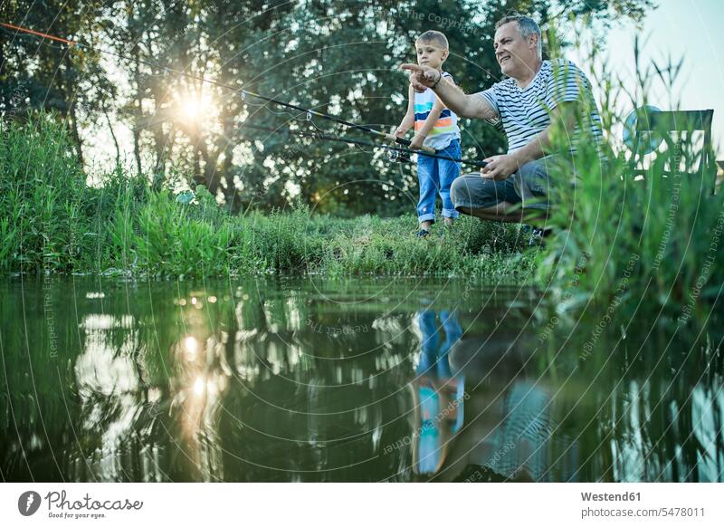 Grandfather and grandson fishing together at lakeshore grandfather grandpas granddads grandfathers grandsons angling Lakeshore Lake Shore lakeside grandparents
