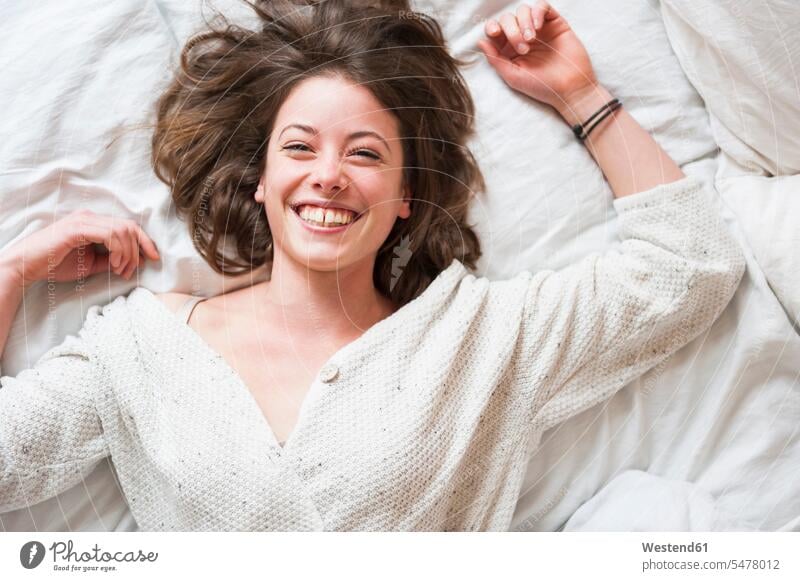 Cheerful young woman lying in bed at home color image colour image indoors indoor shot indoor shots interior interior view Interiors day daylight shot