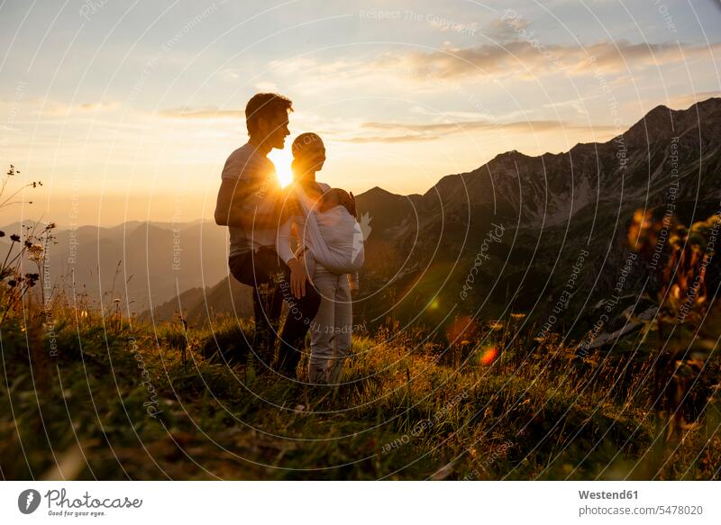 Germany, Bavaria, Oberstdorf, family with little daughter on a hike in the mountains at sunset families hiking daughters holding people persons human being