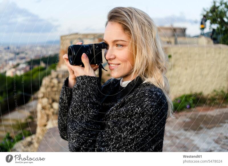 Young woman taking pictures above the city at sunrise, Barcelona, Spain human human being human beings humans person persons caucasian appearance