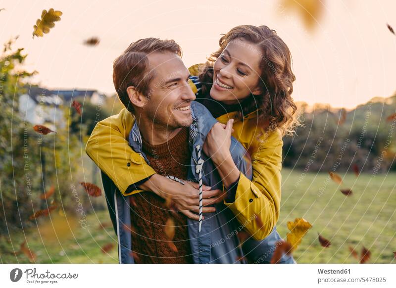 Man giving woman a piggyback ride outdoors in autumn human human being human beings humans person persons caucasian appearance caucasian ethnicity european 2