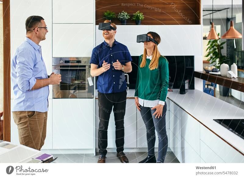 Couple wearing VR glasses shopping for a new kitchen in showroom human human being human beings humans person persons client clientele clients customers