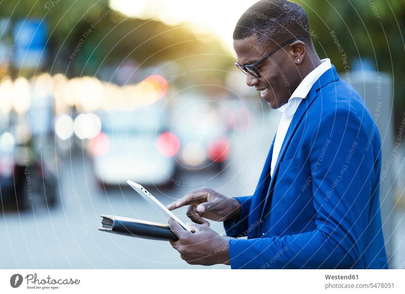Young businessman wearing blue suit jacket and using his digital tablet at a street business life business world business person businesspeople Business man