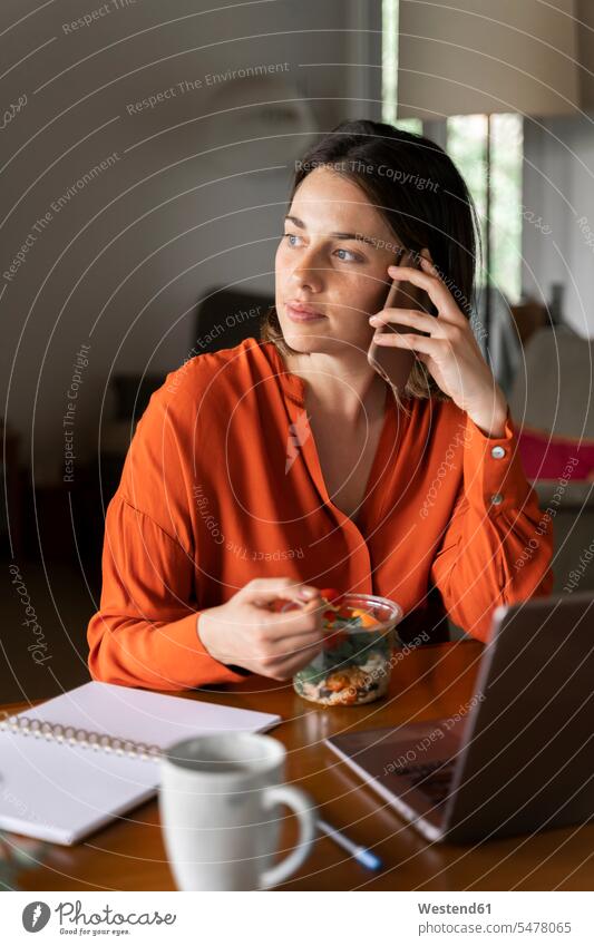 Businesswoman talking on mobile phone while eating salad at home color image colour image indoors indoor shot indoor shots interior interior view Interiors day