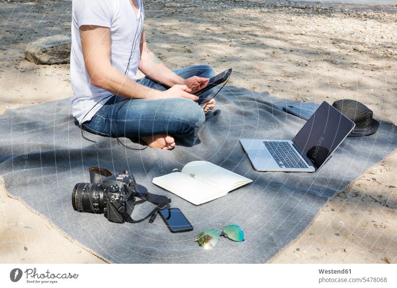 Man sitting on blanket at a beach using tablet Seated digitizer Tablet Computer Tablet PC Tablet Computers iPad Digital Tablet digital tablets man men males