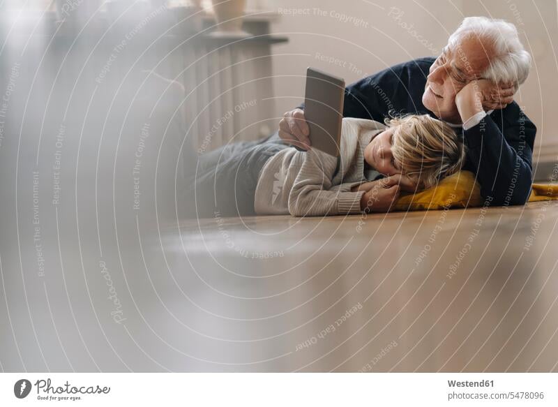 Grandfather and grandson lying on the floor at home using a tablet generation cushions jumper sweater Sweaters video closeness propinquity laying down lie