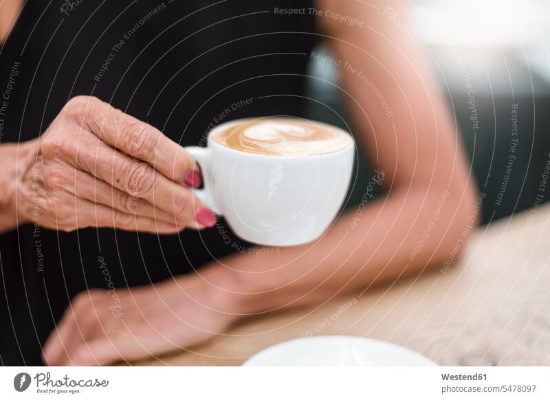 Close-up of senior woman holding a cup of cappuccino senior women elder women elder woman leaning Cappuccino cappucino females dress dresses senior adults