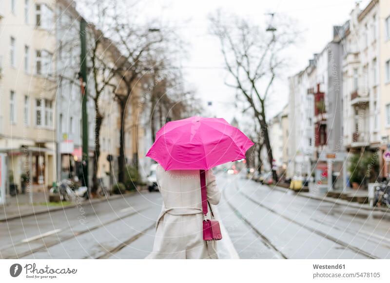 Rear view of a woman with pink umbrella walking on street business life business world business person businesspeople business woman business women