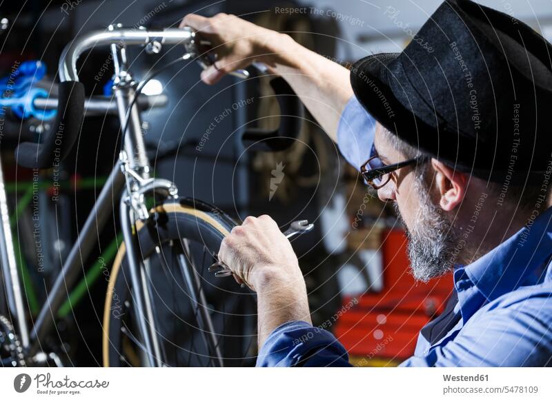 Man working on bicycle in workshop bikes bicycles At Work man men males craft crafts handwork handcraft hand work manual labour manual work handicraft Adults